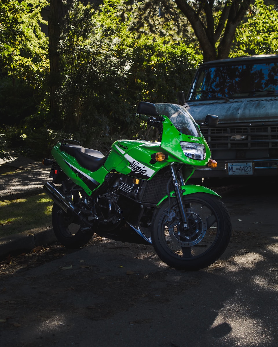 a green motorcycle parked in front of a truck